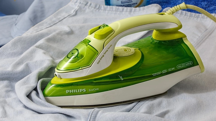 正在熨燙衣物的 Philips 蒸氣熨斗,展示如何平整衣物皺褶與制服保養技巧。